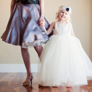 A photo of a flower girl wearing a cotton flower girl dress with a very full tulle skirt