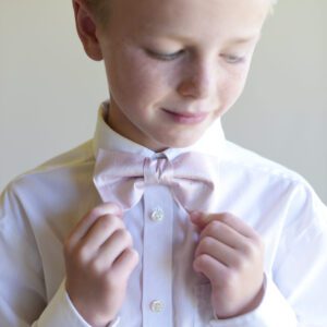 A photo of a pageboy wearing a pure silk blush coloured bow tie
