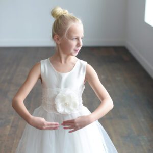 A photo of a 9 year old flower girl wearing a silk dress with a full tule skirt and a lace belt