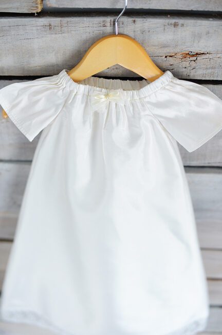 A photo of a perfectly simple pure silk christening gown with a lace hem