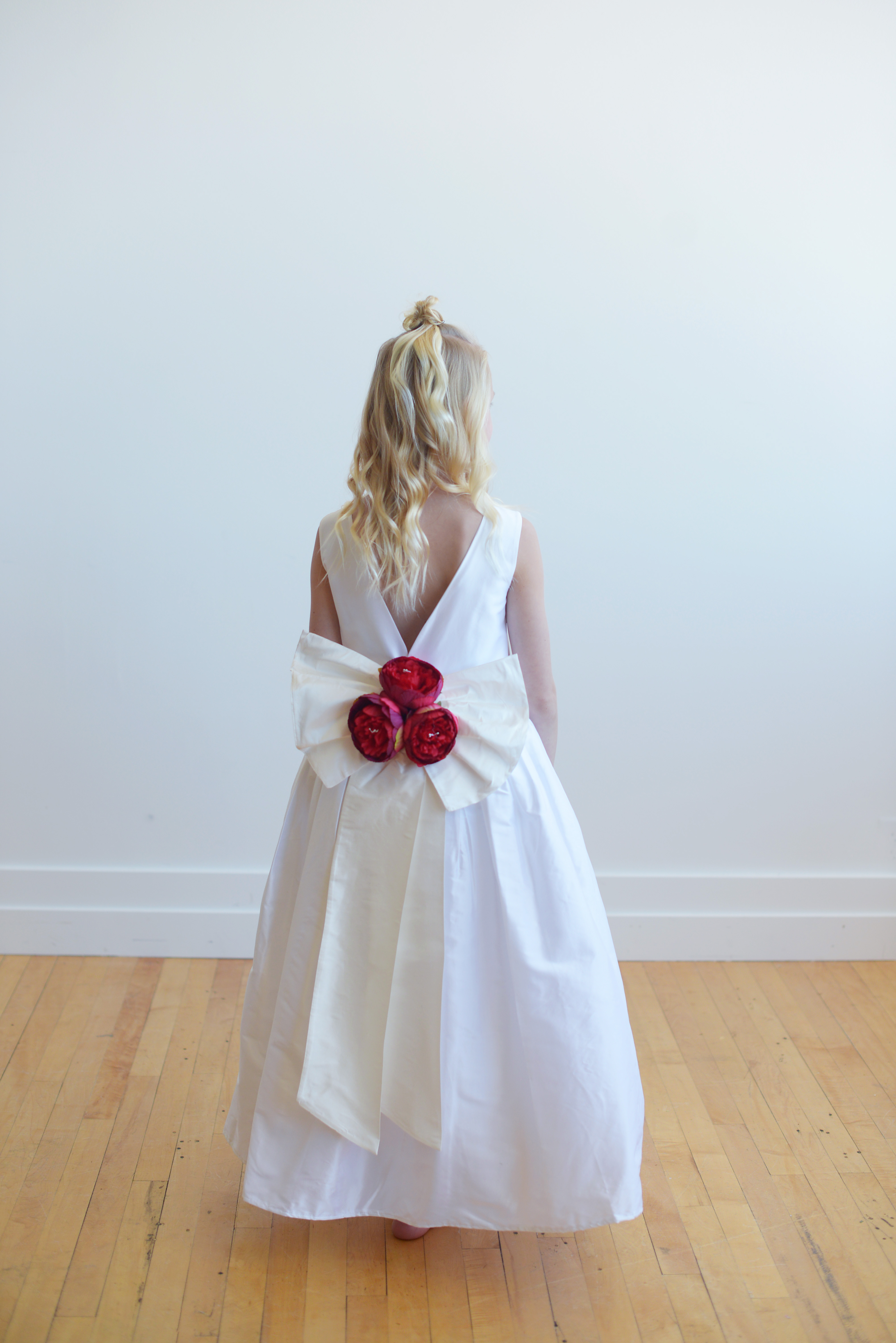 A photo of the back of a hand made pure silk flower girl dress with red flowers