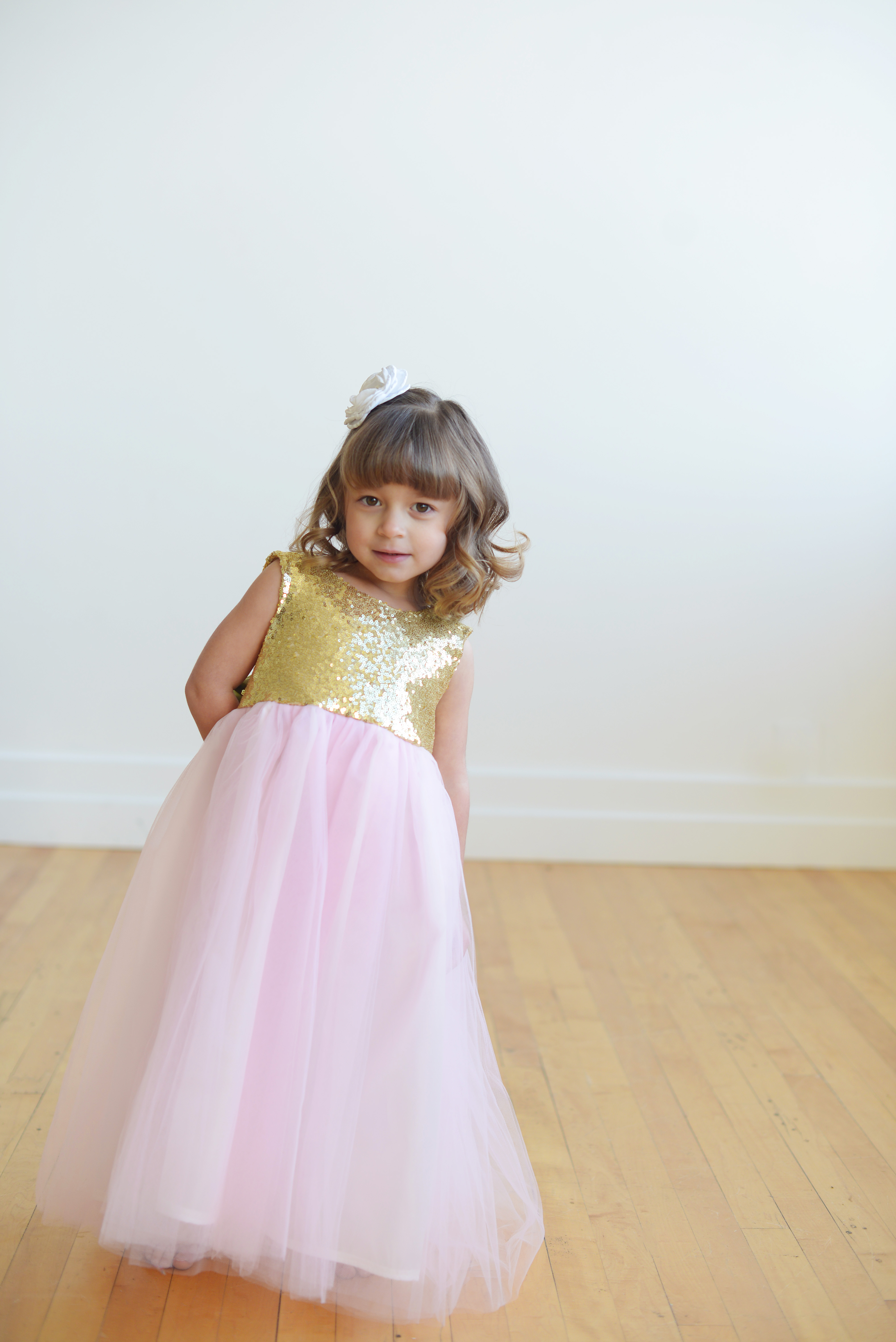 A pink and gold sequin flower girl dress with oversized bow