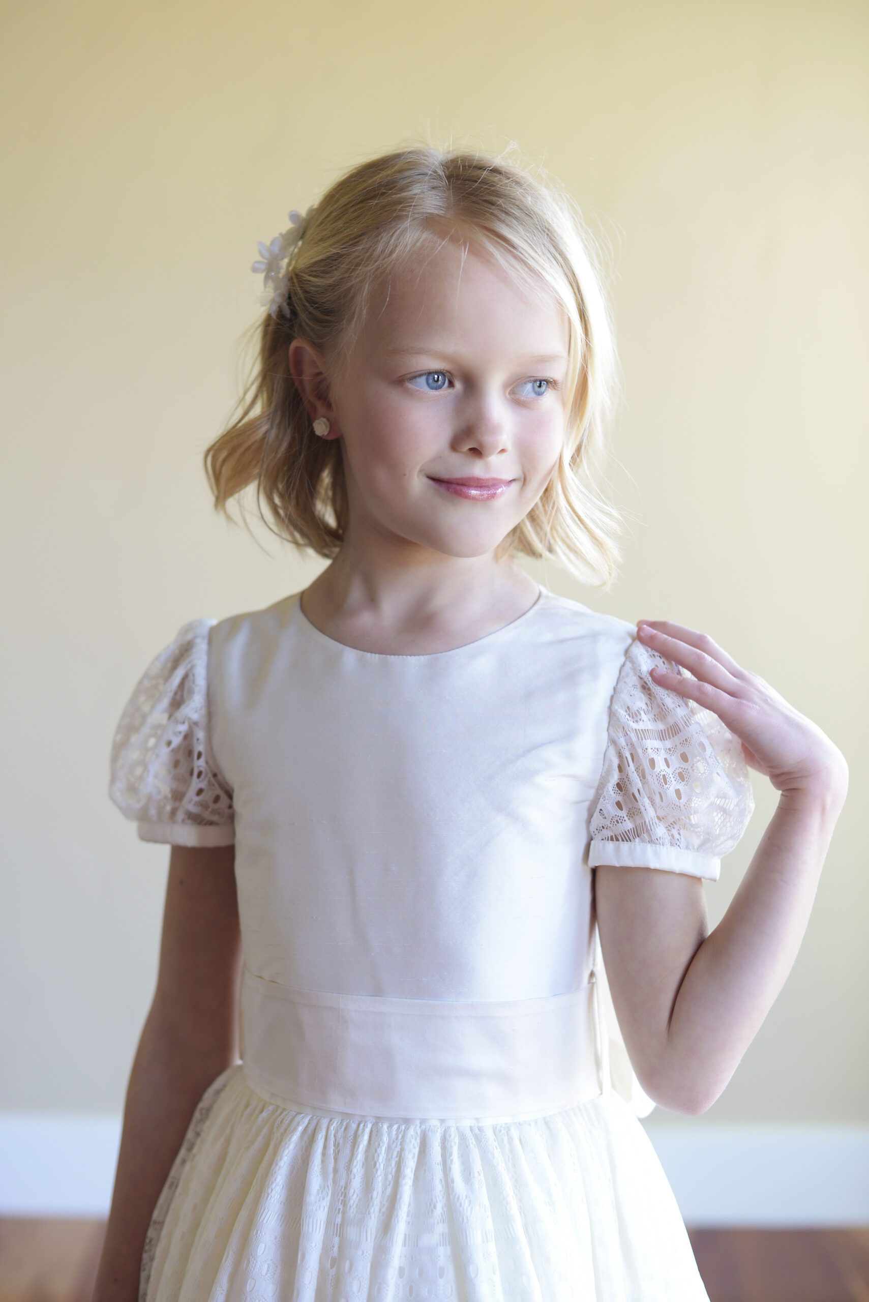 A photo of a girl wearing a traditional flower girl dress in a heavy silk and lace
