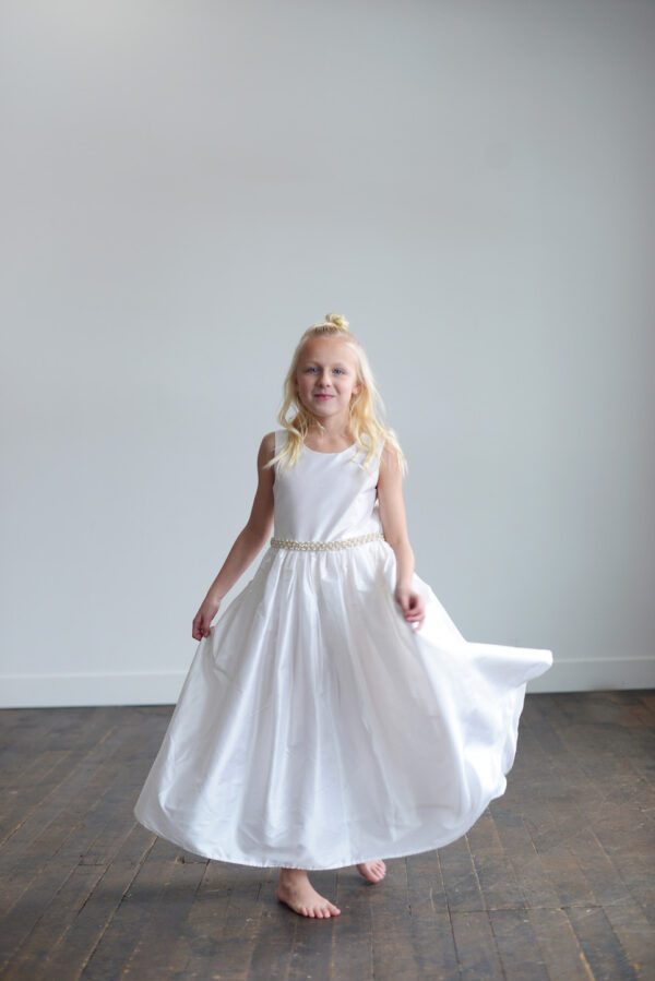 A white silk first communion dress or flower girl dress with a pearl trim