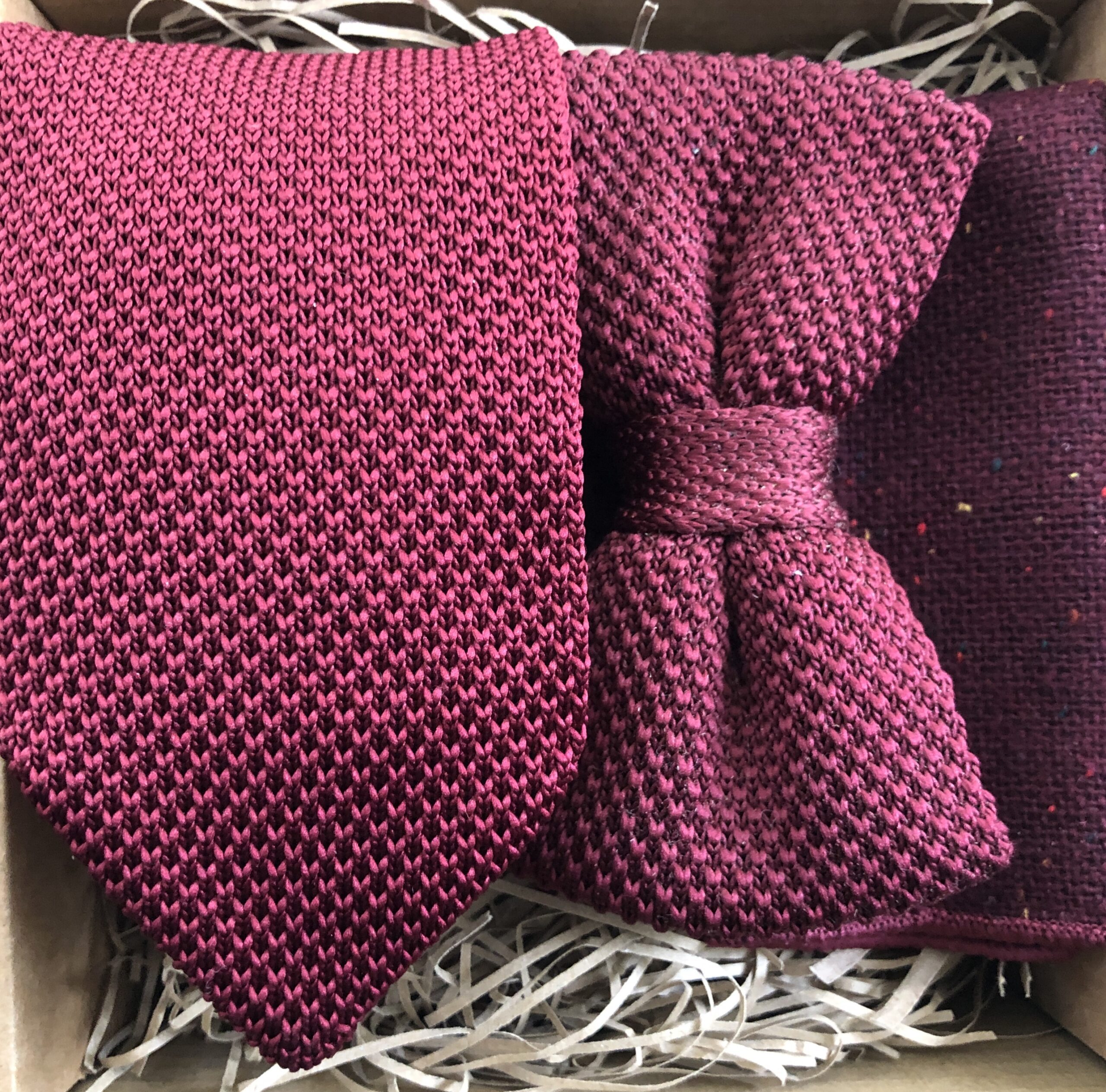 A photo of a mulberry red tie, bow tie and pocket square perfect as groomsmen gifts