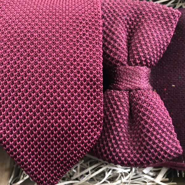 A close up photo of a men's deep red knitted tie and bow tie