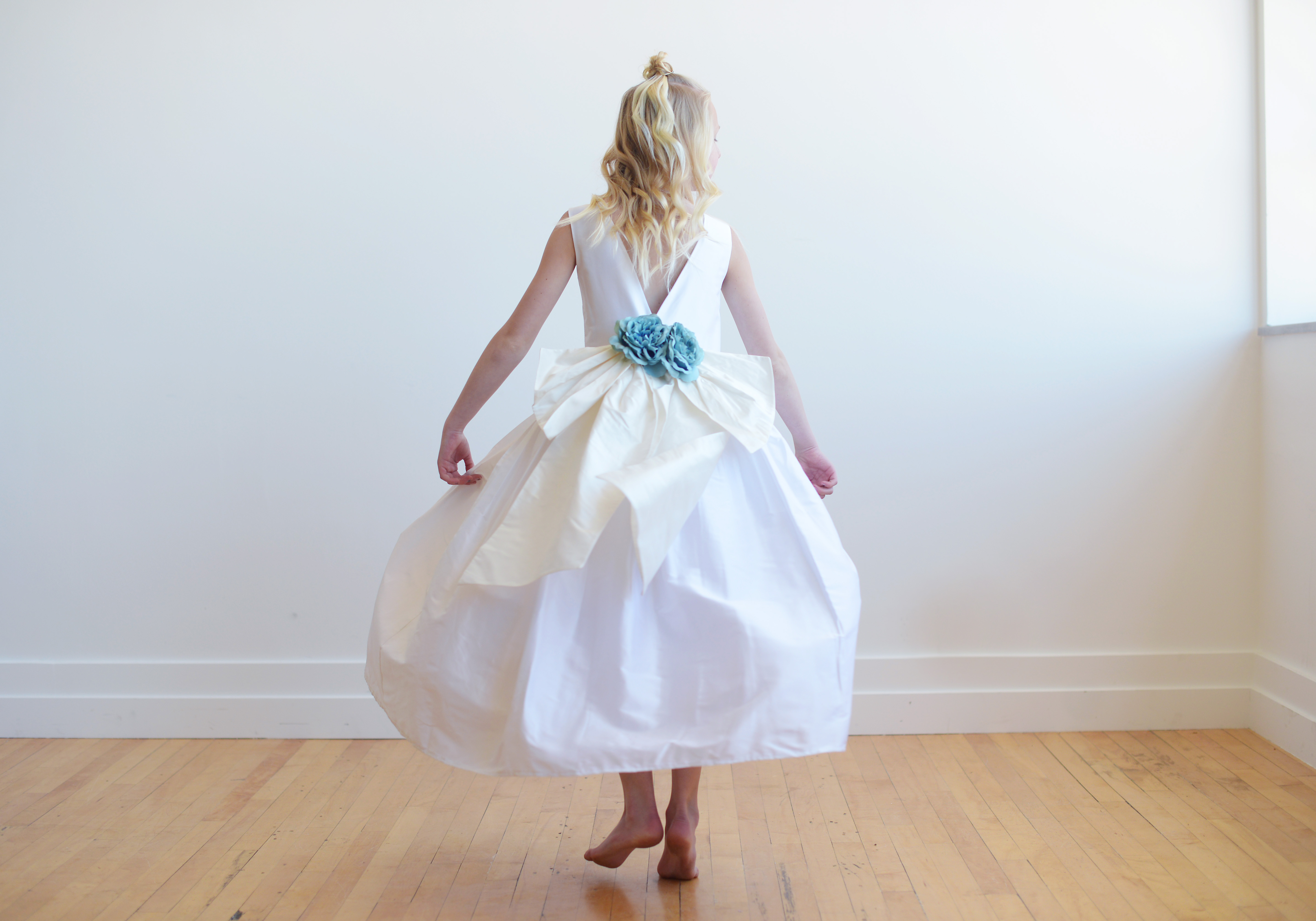 A photo of a girl wearing a cotton flower girl dress with a baby blue bow