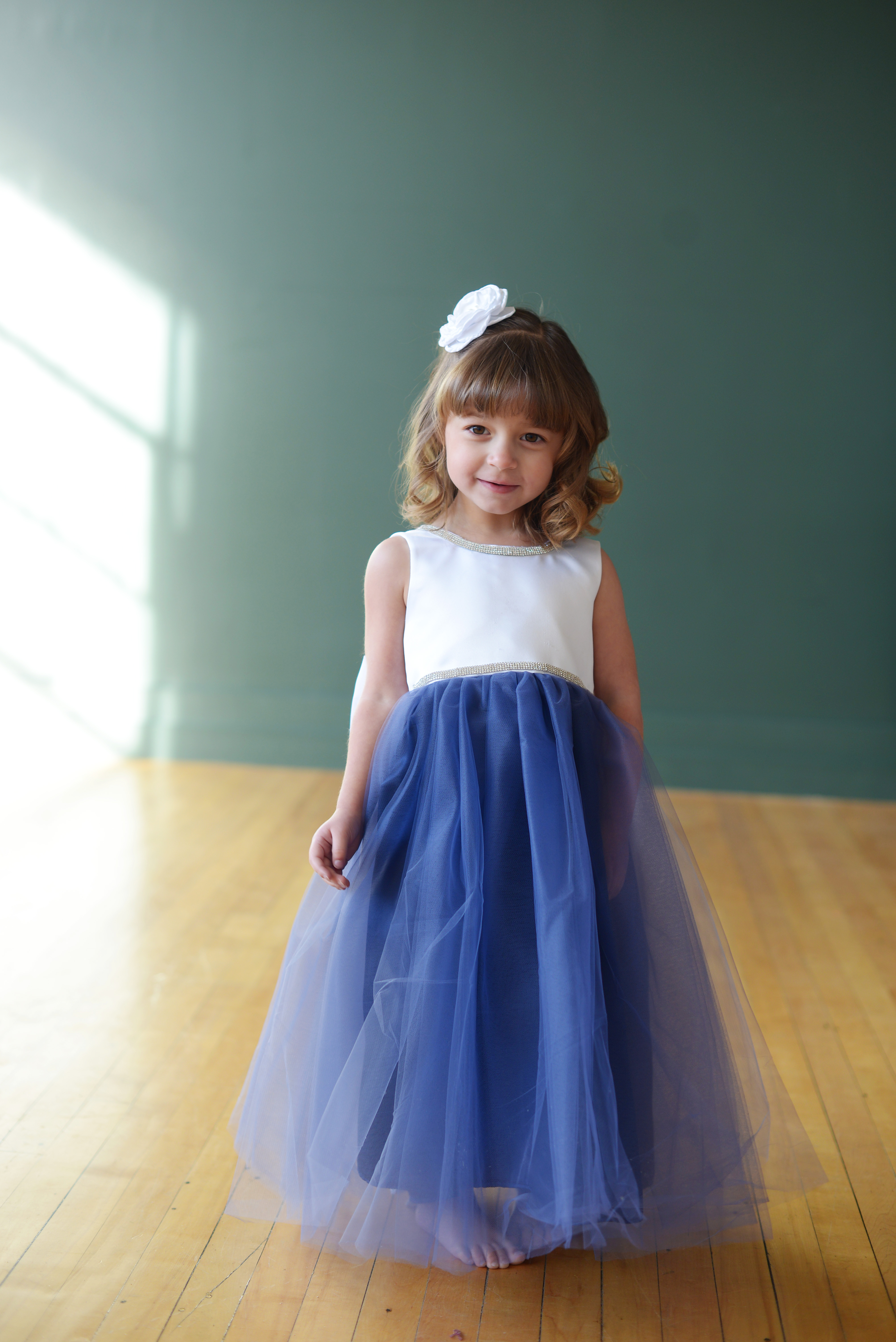 A blue and white flower girl dress with a tulle skirt and diamante trim