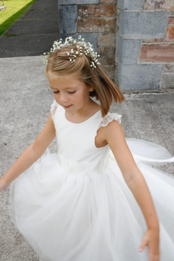 A photo of a flower girl wearing a silk, lace and tulle princess dress in ivory