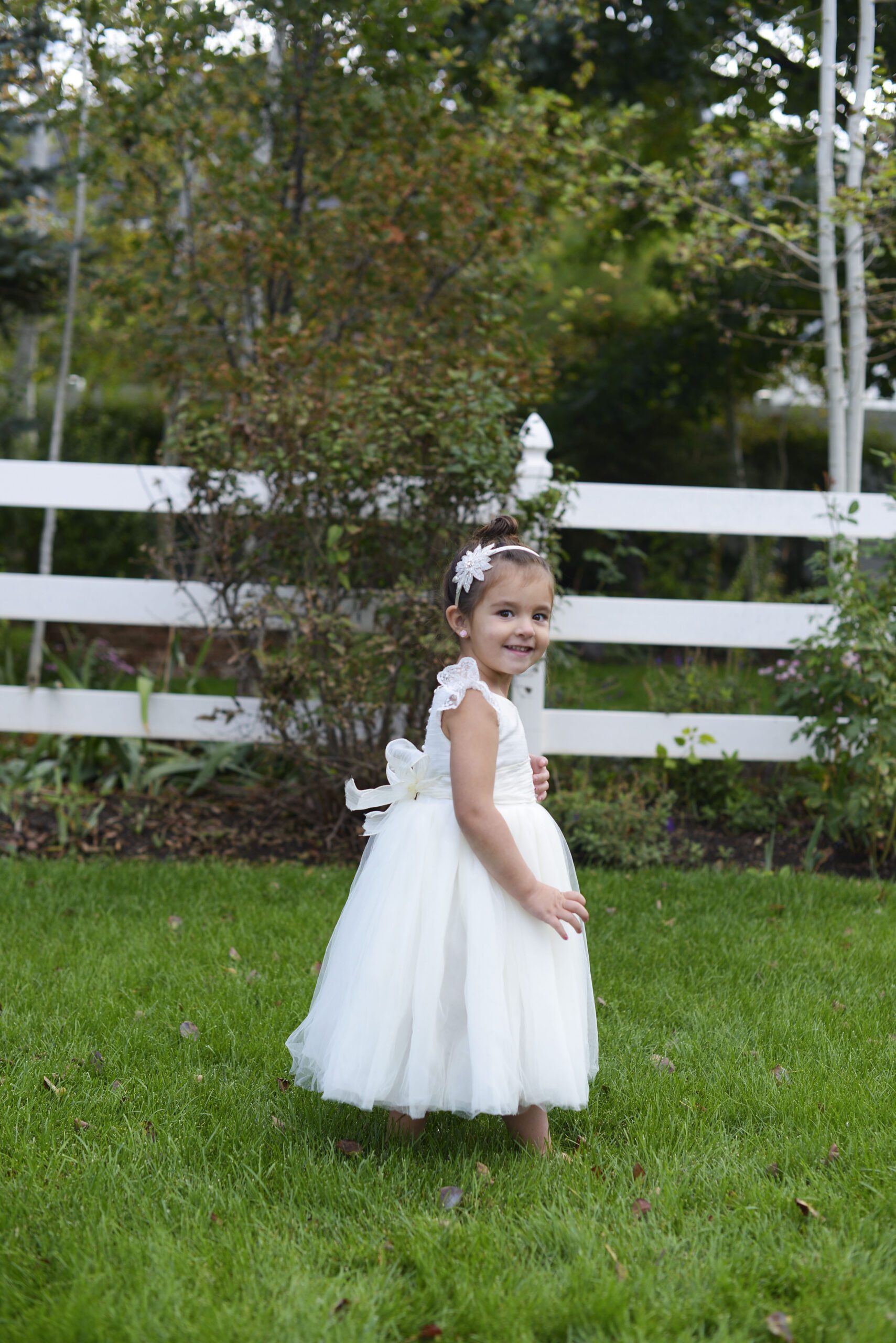 A photo of a girl wearing an ivory lace flower girl dress with full tulle skirt and a star diamante headband
