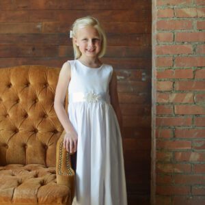 A photo of a flower girl in a white cotton summer dress with a diamante motif