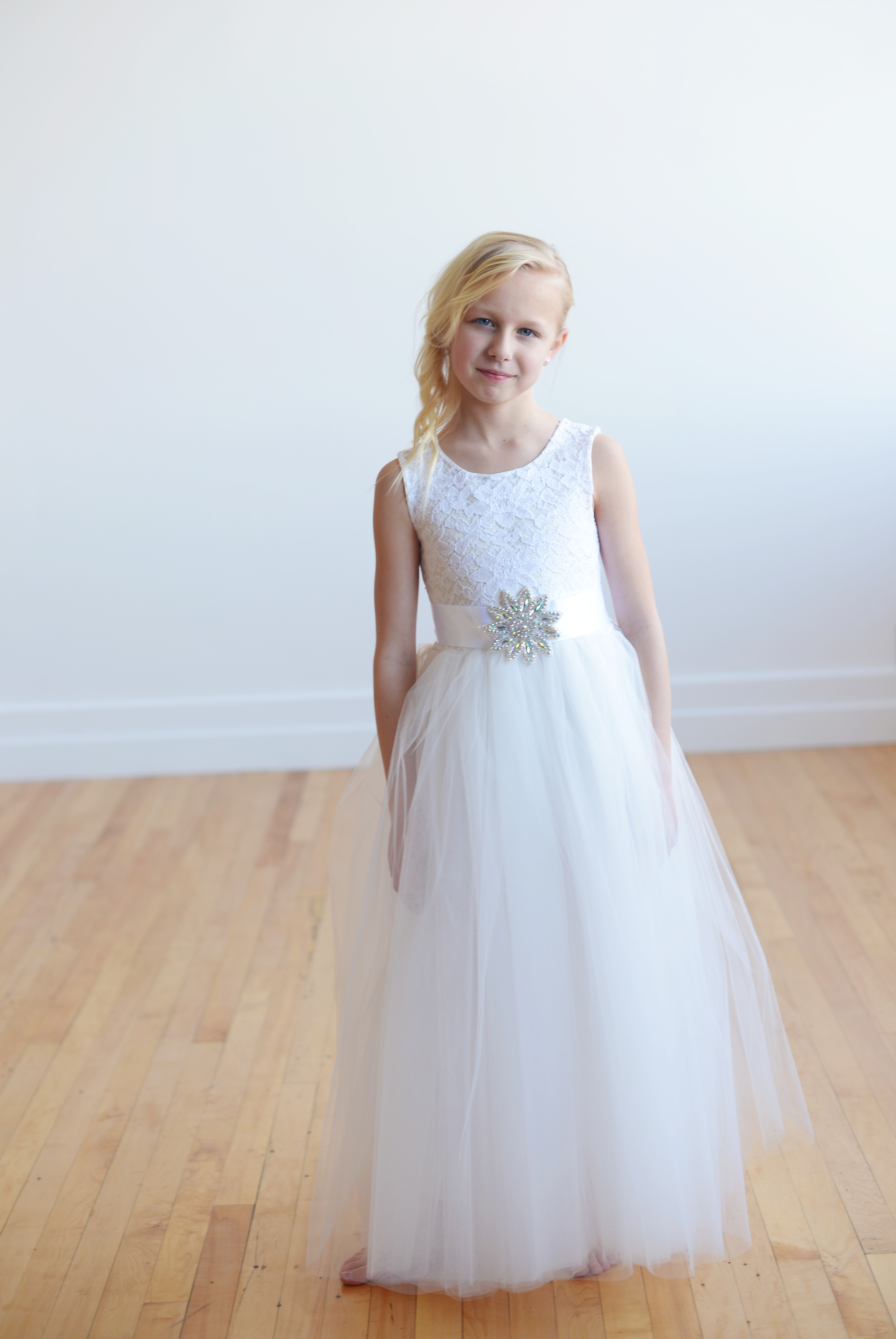 A photo of a white flower girl dress with a lace bodice