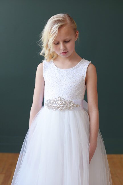 A photo of an ivory lace and tulle flower girl dress with a daimante motif on the sash