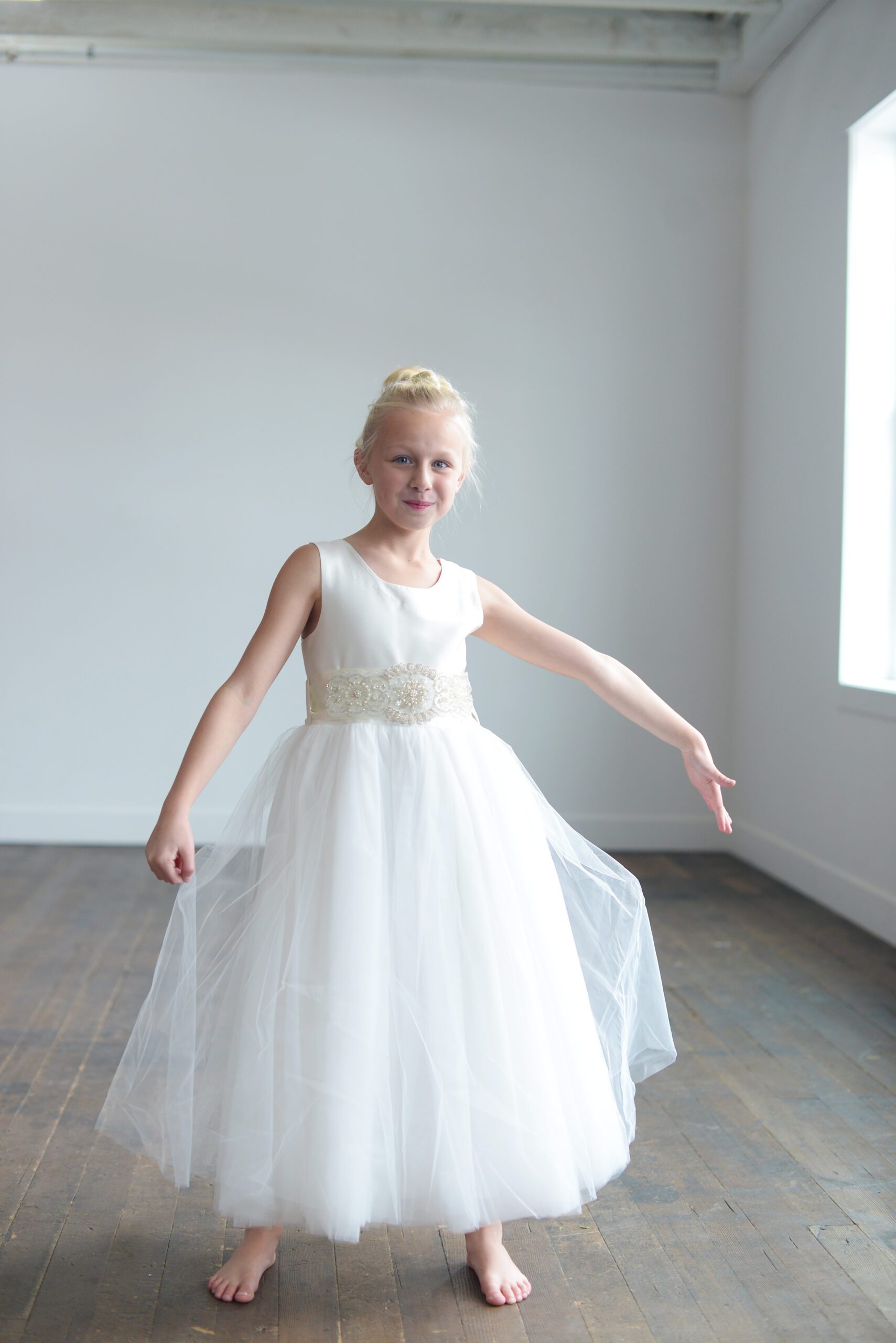 A photo of a flower girl in an ivory tulle and silk dress, handmade to measure.
