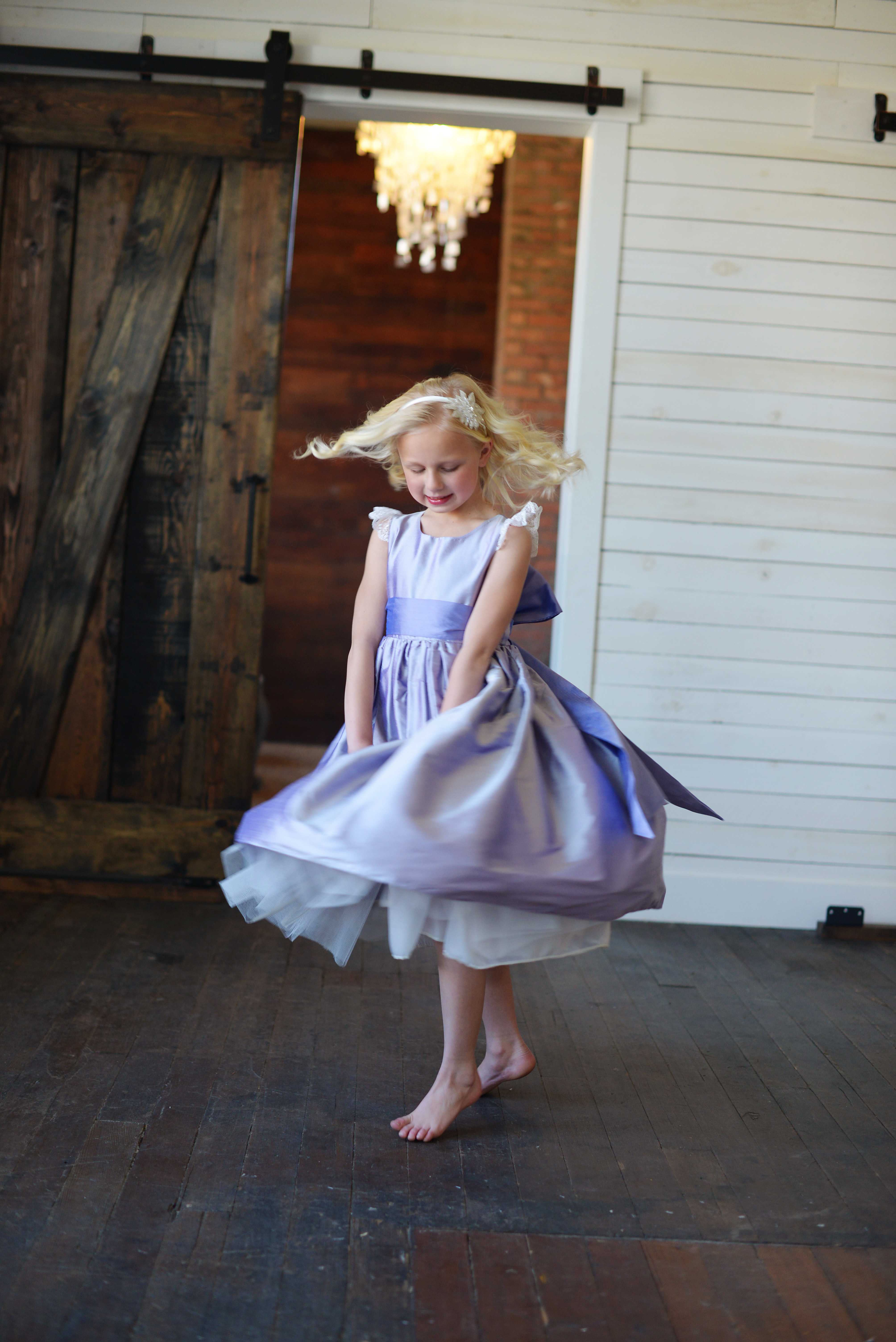A photo of a flower girl dancing in a purple silk dress