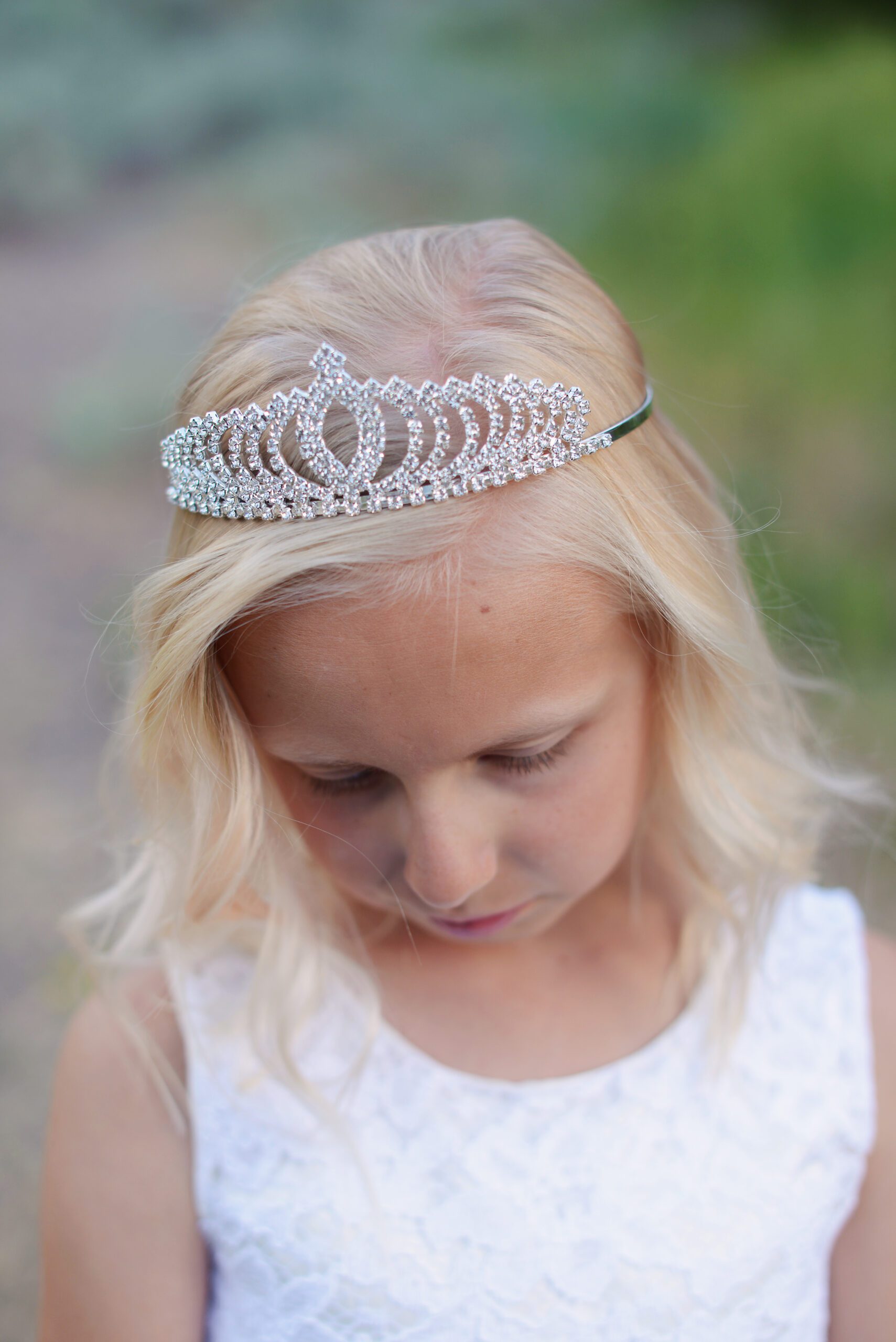 A photo of a flower girl wearing a rhinestone tiara and an ivory flower girl dress