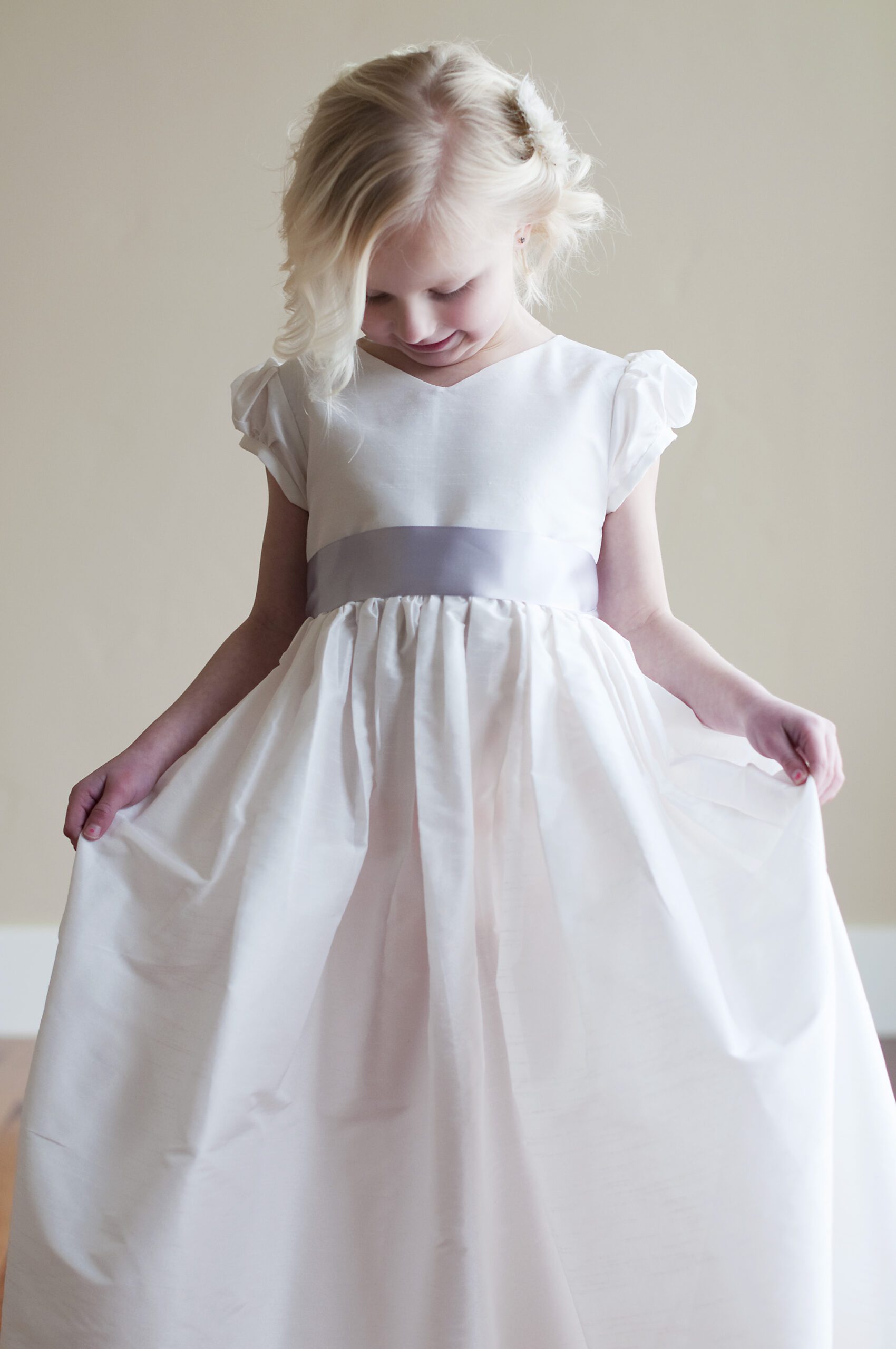A photo of a white flower girl dress in cotton with a v neck and is made to measure
