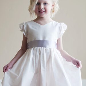 A photo of a girl wearing a cotton flower girl dress with a silver sash