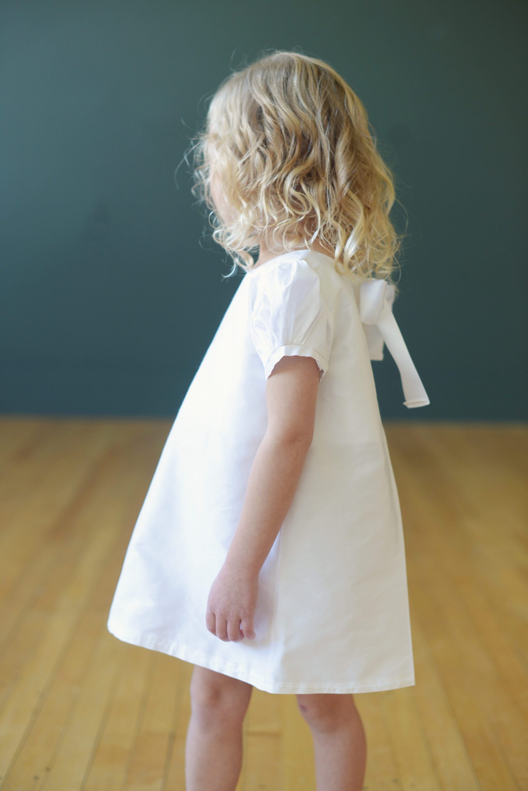 A photo of a 3 year old flower girl wearing a white silk knee length dress