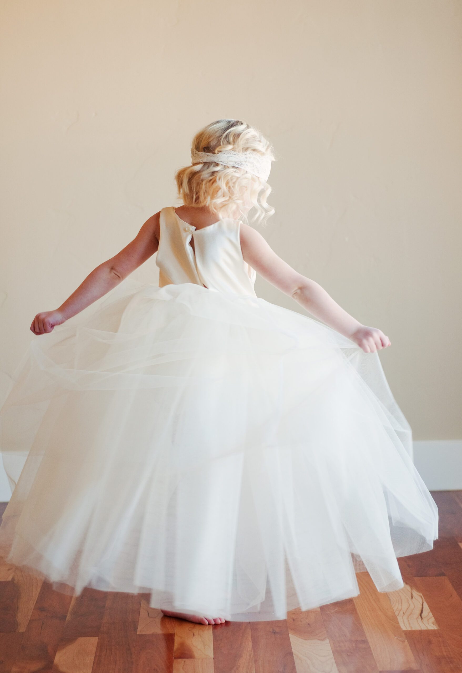 A photo of the back of a ballerina dress in ivory tulle worn by a 3 year old girl