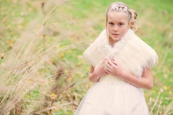 A photo of a flower girl wearing a feathered shawl in ivory