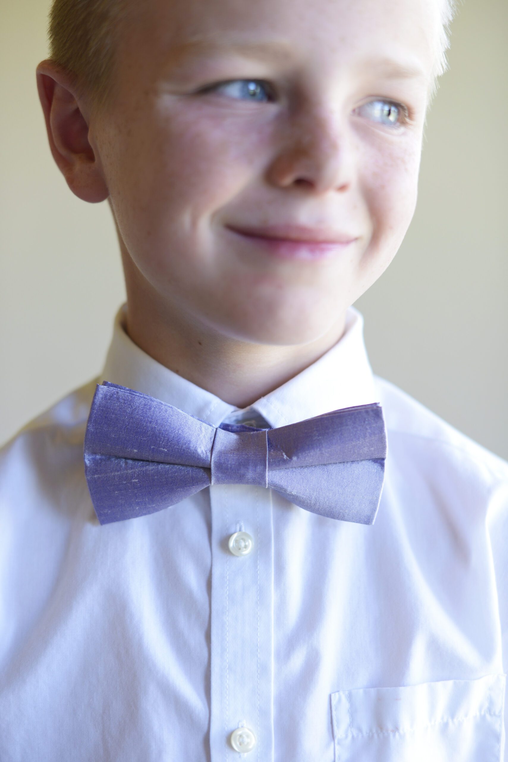 A photo of a pageboy wearing a pre-tied light purple bow tie