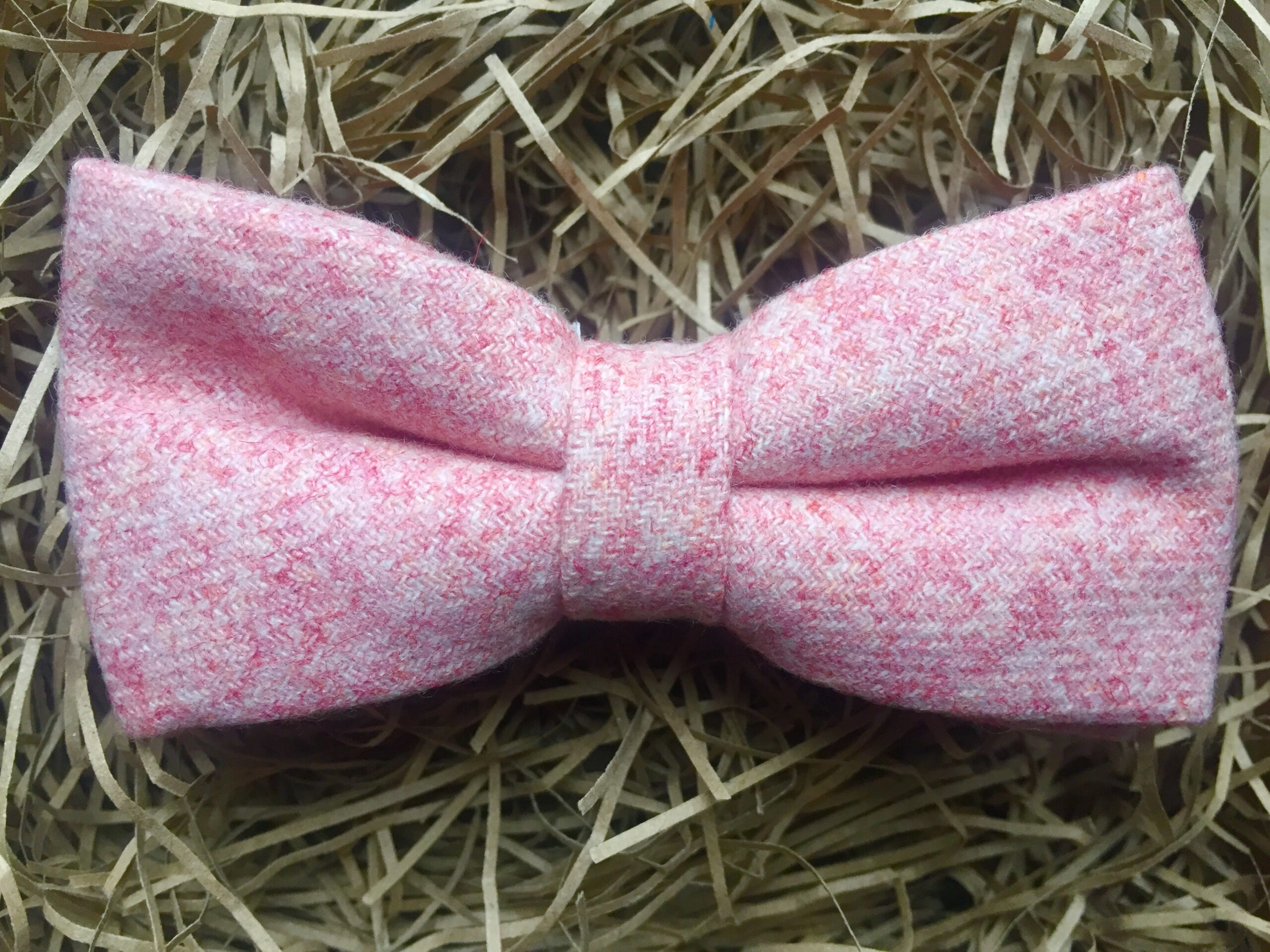 A photo of a pink wool bow tie on an adjustable strap
