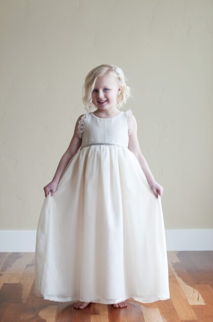 A photo of a three year old flower girl in a chiffon dress with lace sleeves