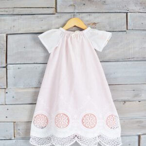 A photo of a white lace christening gown with a pink underlay