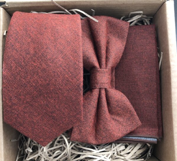 A photo of a burnt orange tie, bow tie and pocket square ideal as groomsmen gifts