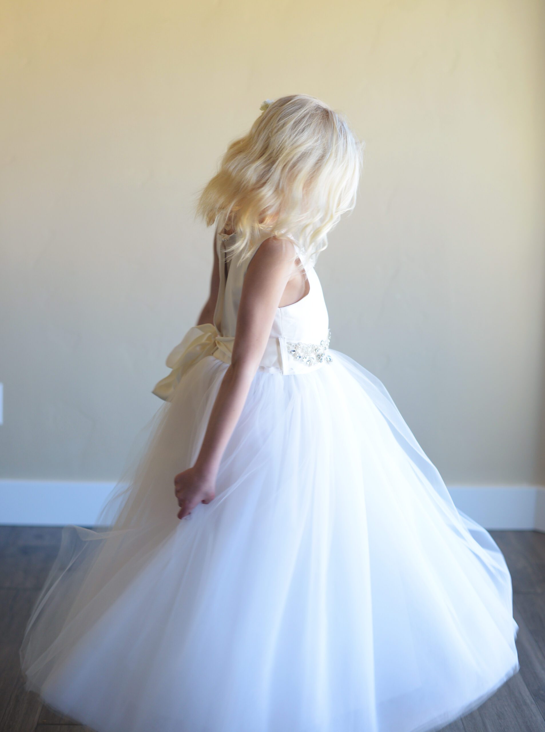 A photo of an 8 year old girl wearing a silk flower girl or first communion dress with a diamante sash