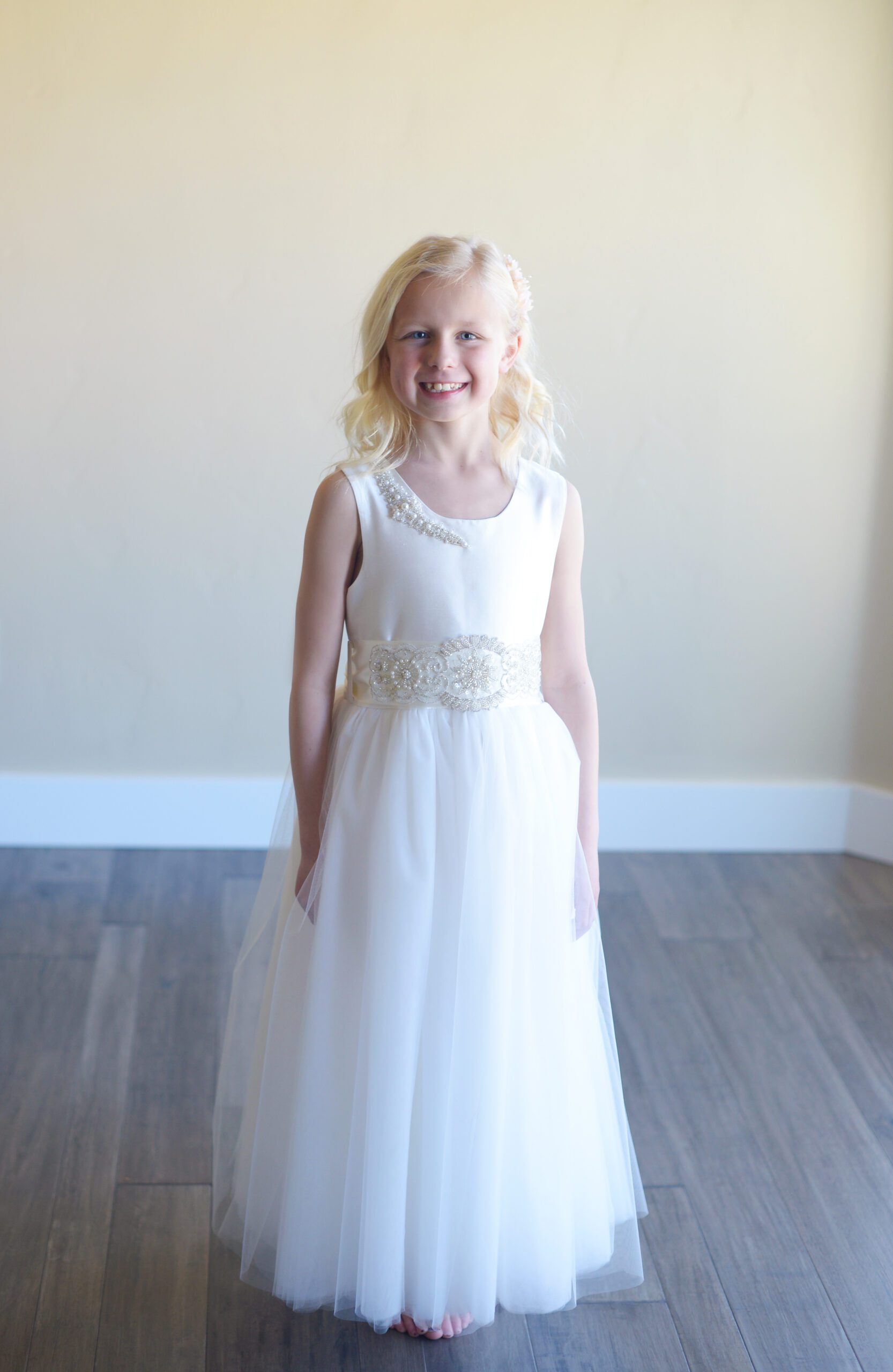 A photo of an 8 year old girl wearing a silk flower girl or first communion dress with a diamante sash