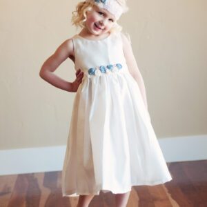 A photo of a cotton flower girl dress in ivory or white with colourful pure silk flowers in pinks and blues