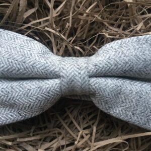 A photo of a grey herringbone wool bow tie on an adjustable strap