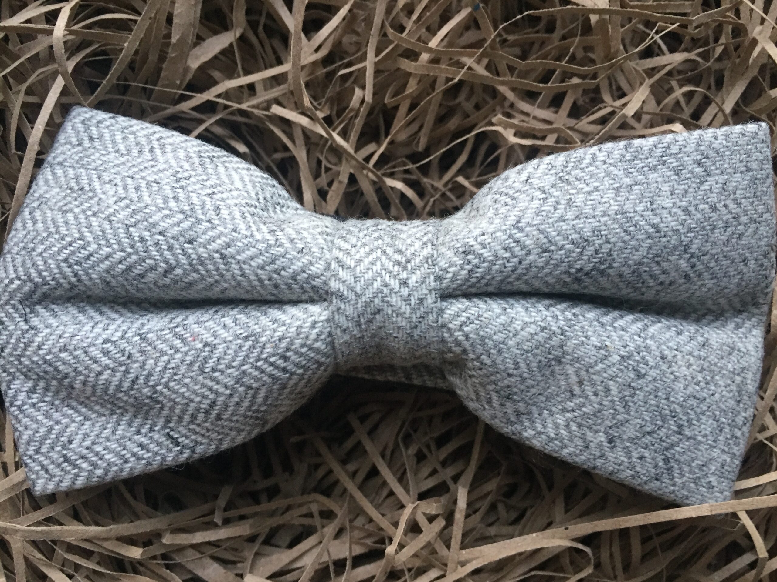 A photo of a grey herringbone wool bow tie on an adjustable strap