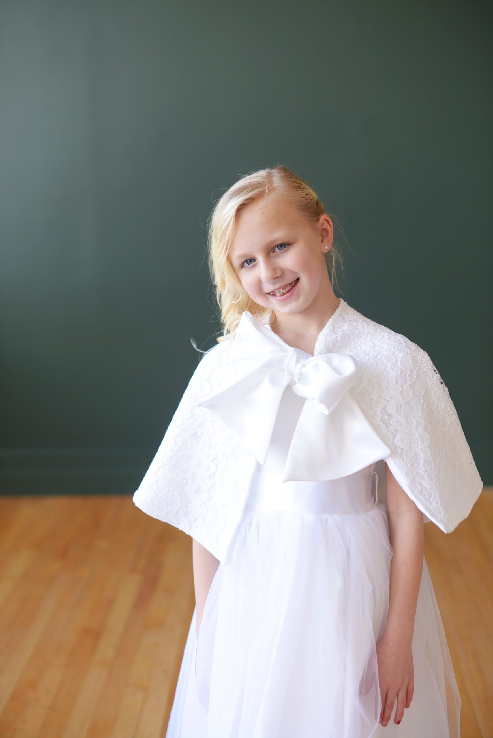 A photo of a girl in a first communion dress with a lace cape for warmth