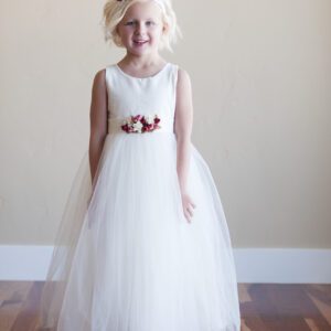 A photo of a flower girl wearing a cotton and tulle dress with pretty red roses