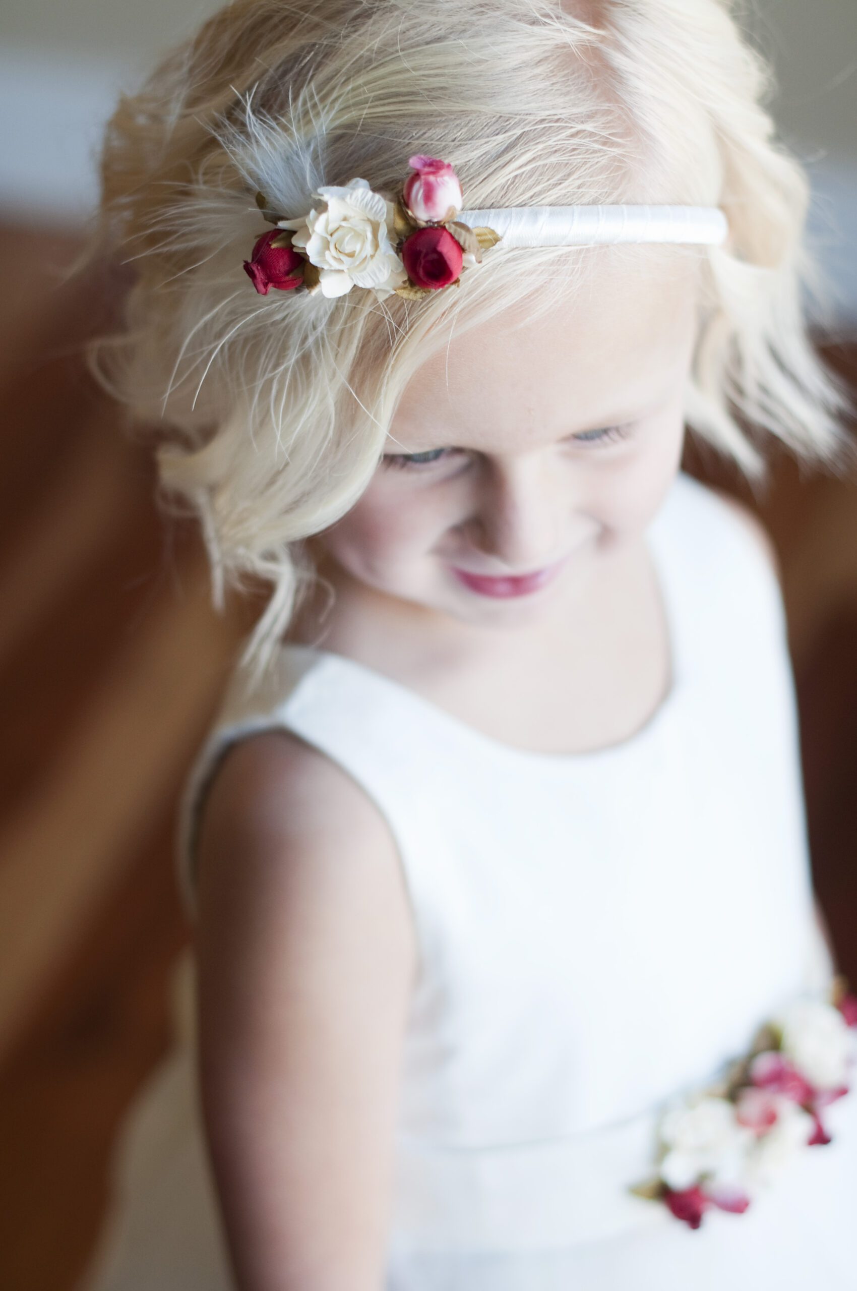 A photo of a flower girl headband in white or ivory satin with pretty red roses