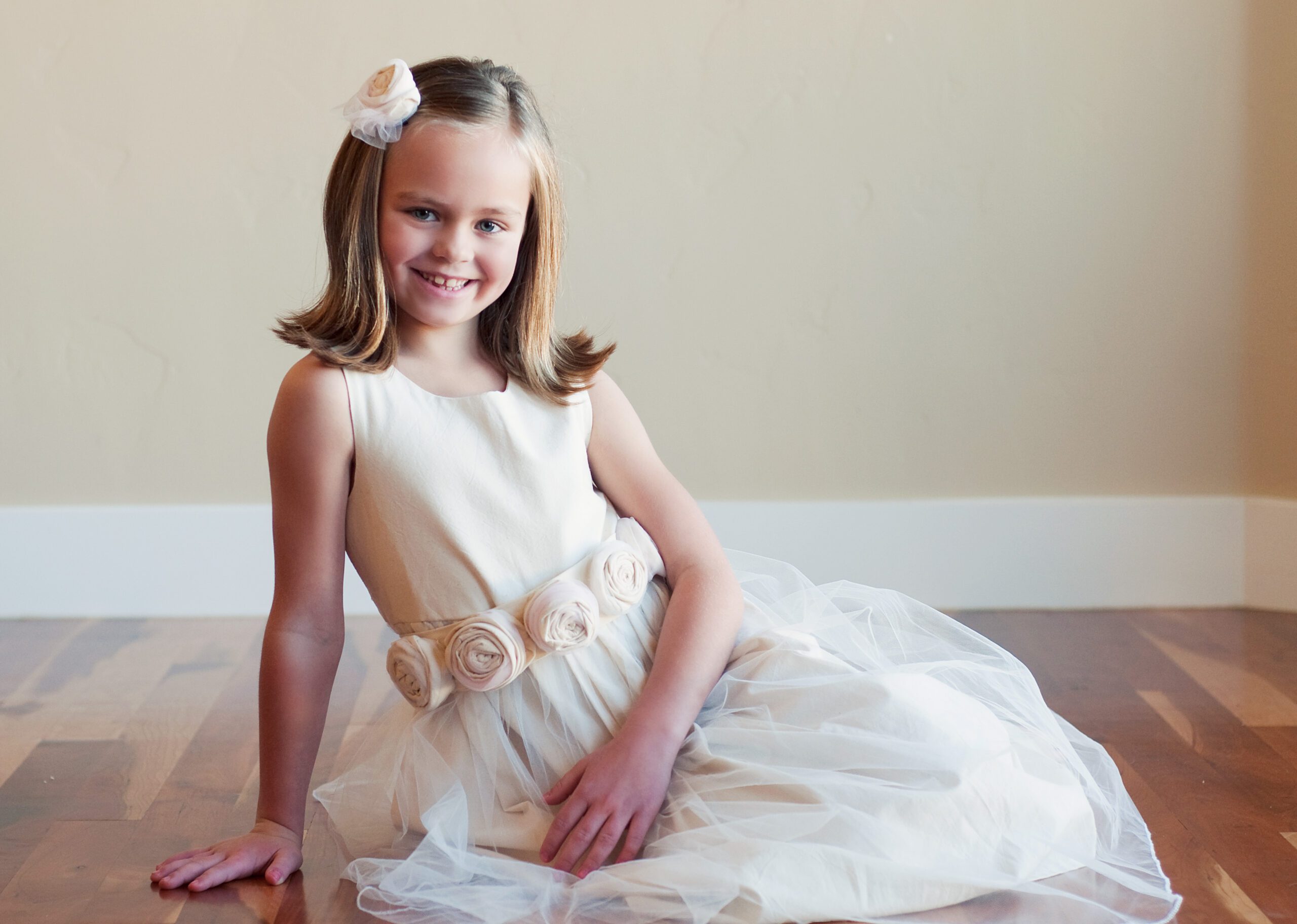 A photo of an eight year old flower girl wearing a cotton dress with roses on the sash