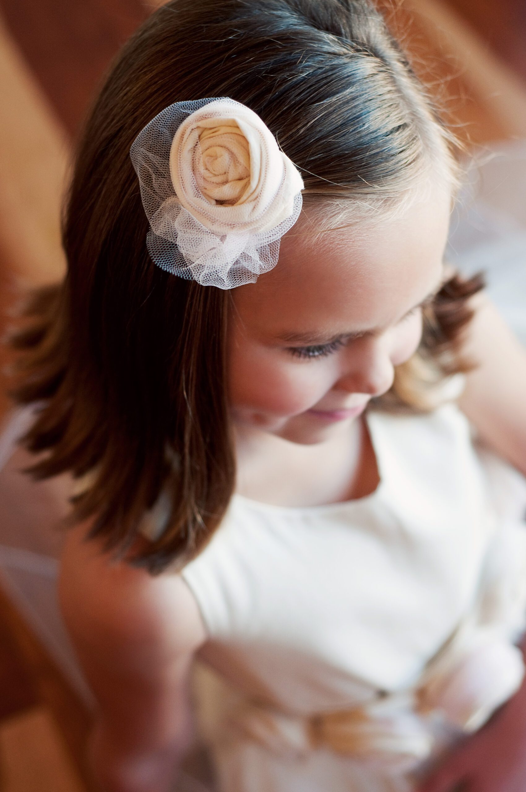 A photo of a cotton flower girl dress in ivory with flowers on the sash