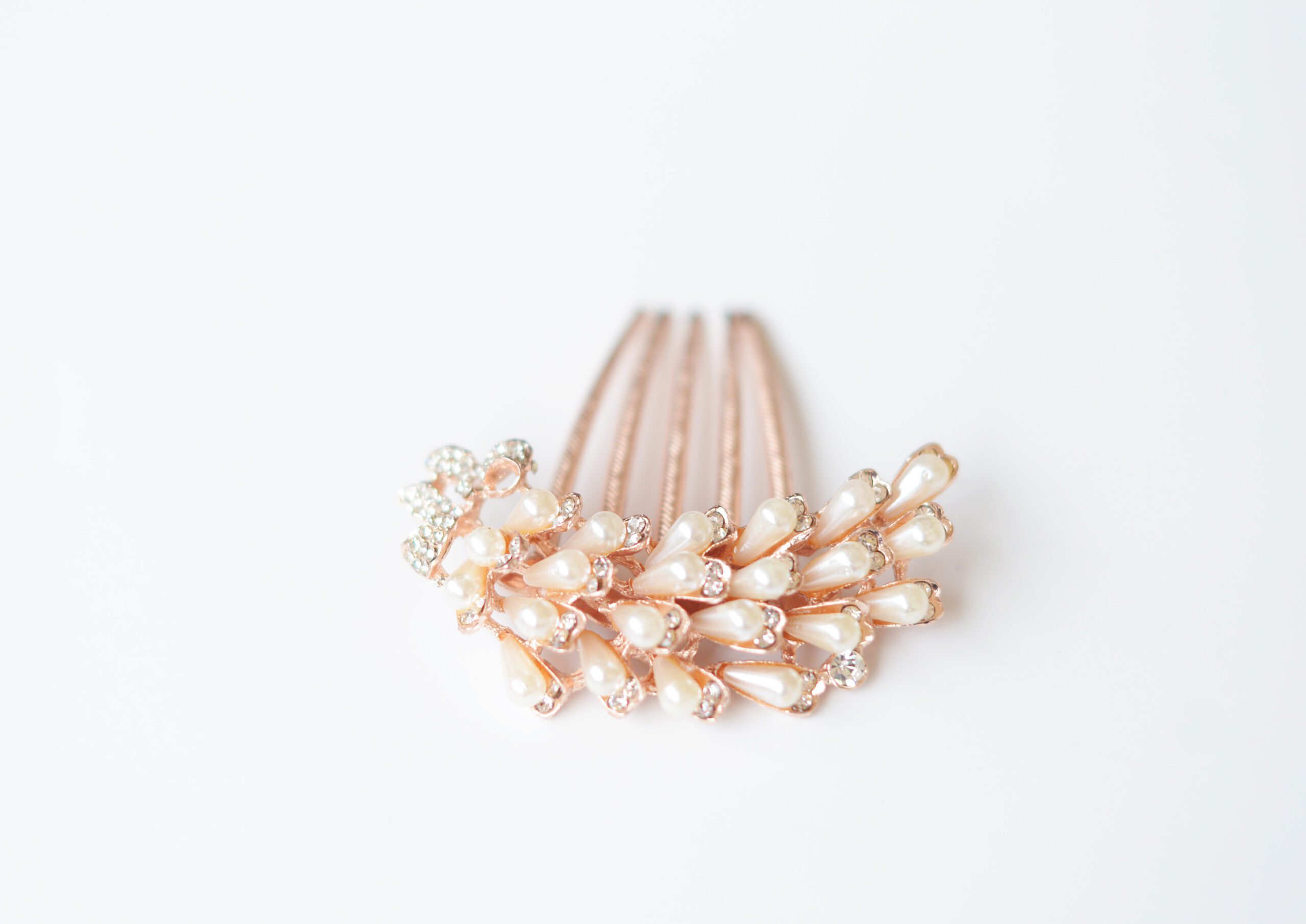 A photo of a bride wearing a rose gold and pearl hair comb