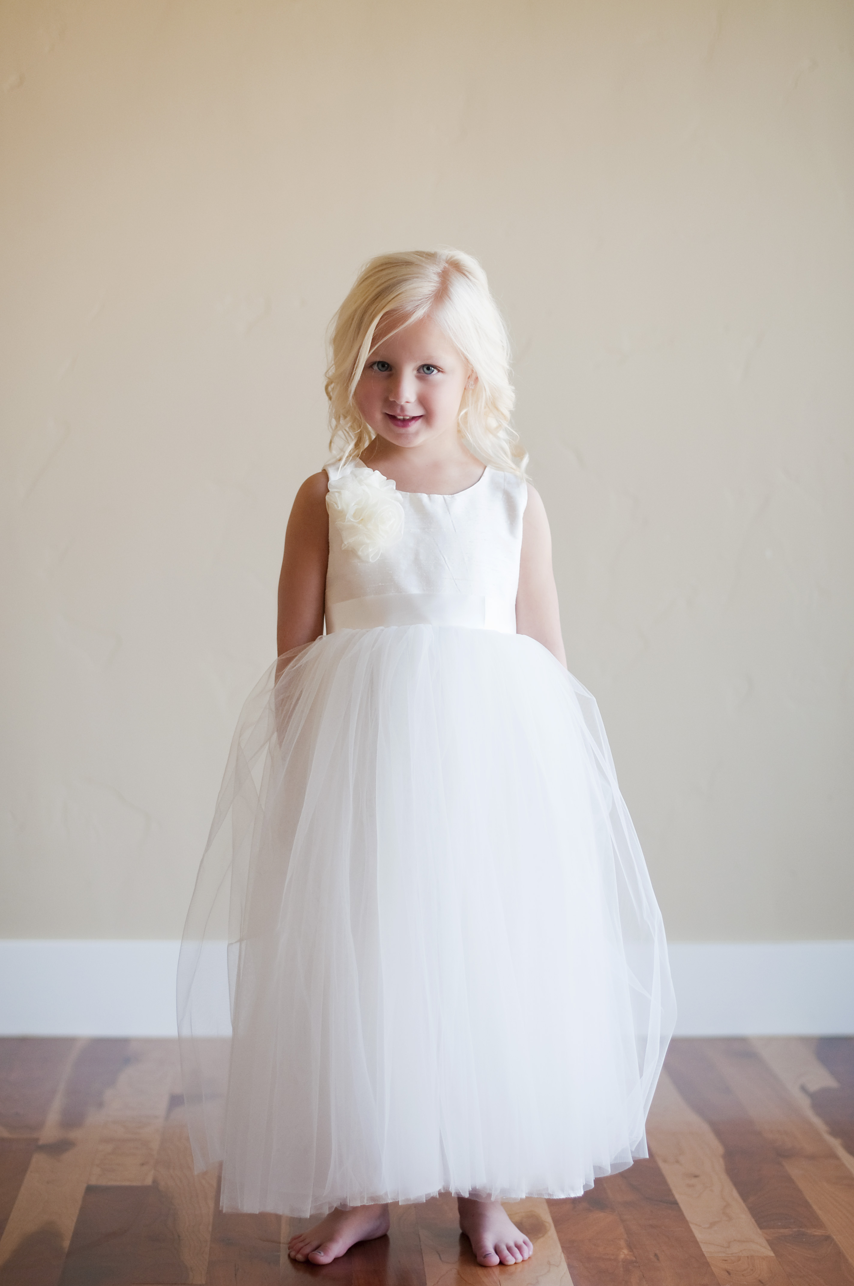 A photo of a three year old. girl wearing a tulle and silk ivory flower girl dress