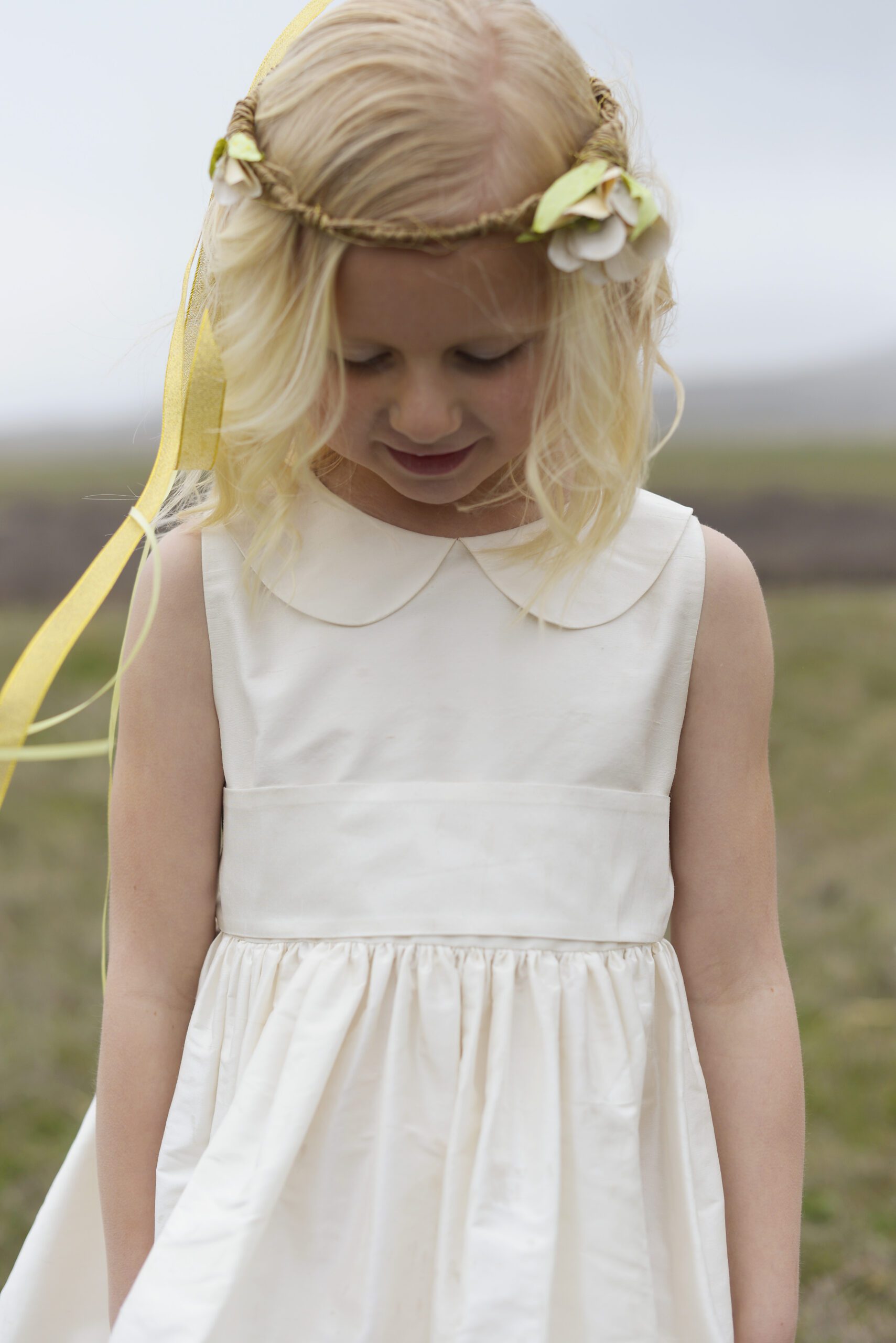 A photo of a 7 year old girl wearing a silk flower girl dress with a Peter Pan collar