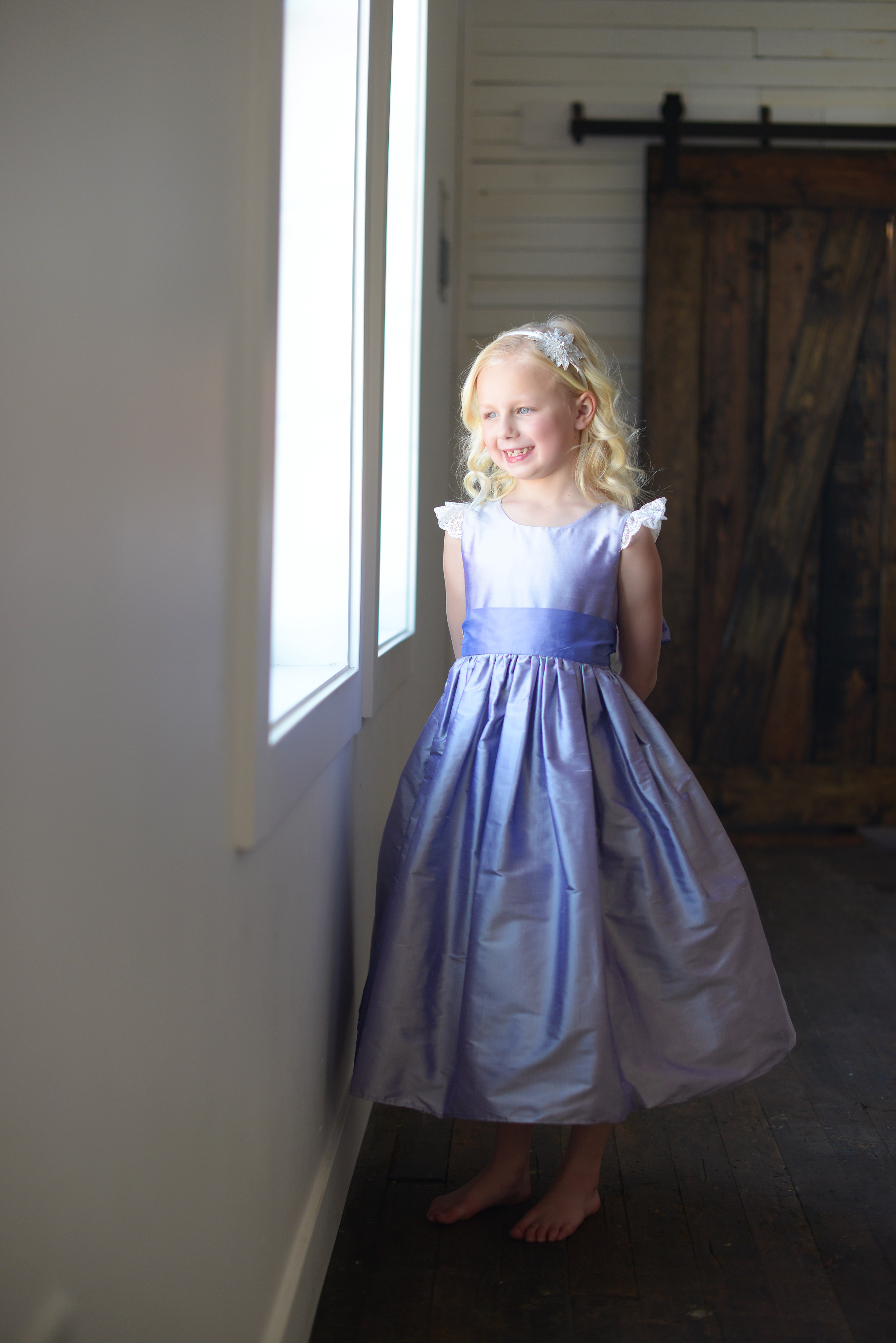 A photo of a purple silk flower girl dress with lace sleeves and a silk sash