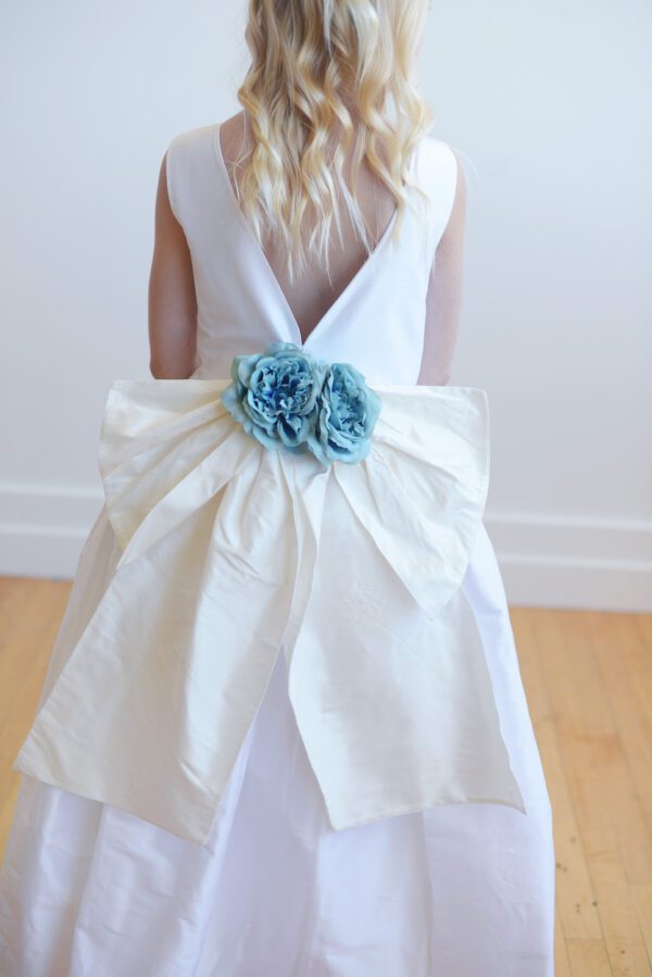 Ivory silk flower girl dress with a blue oversized bow.