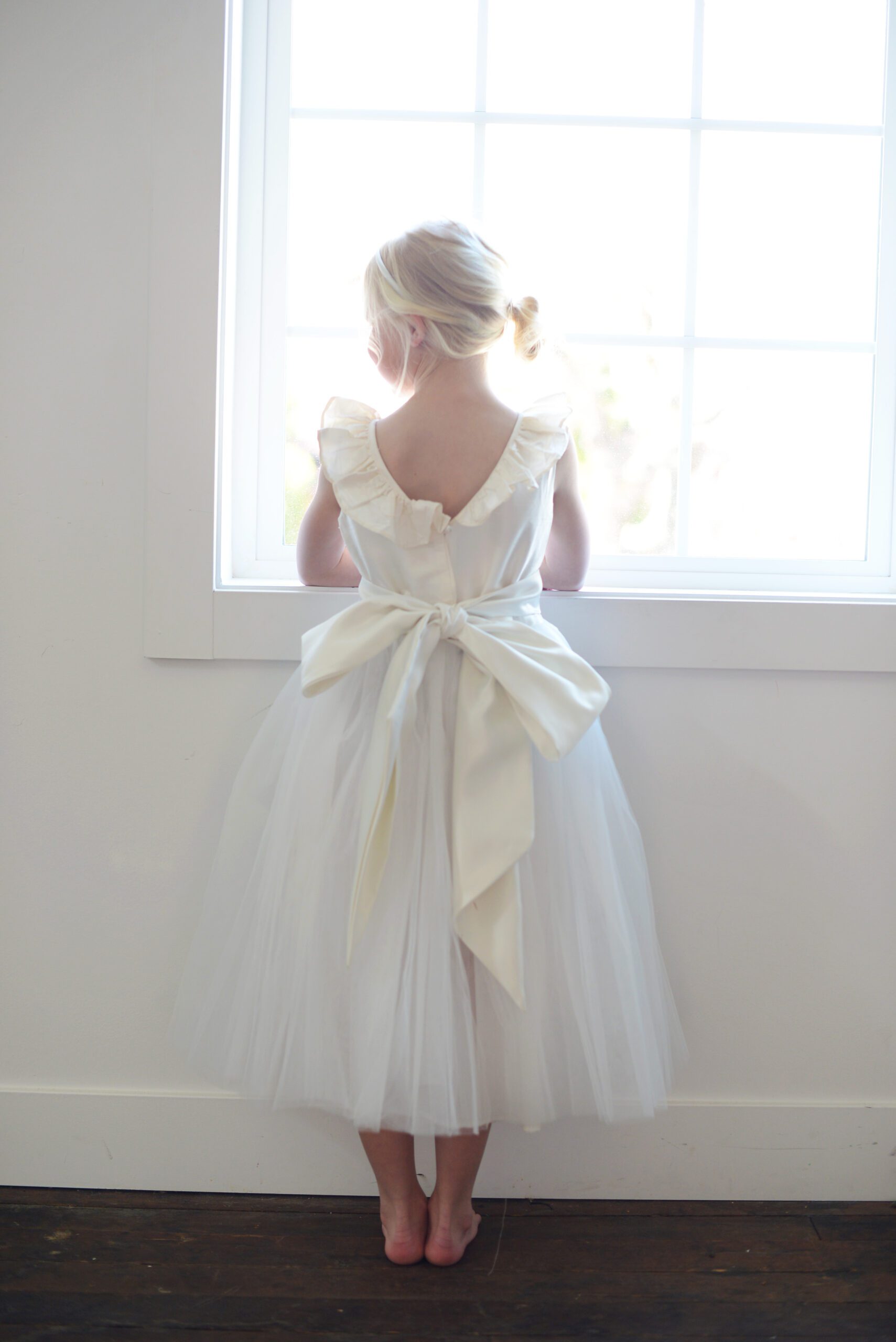 A photo of a ruffle silk ballerina dress in ivory and white silk and with a tulle skirt