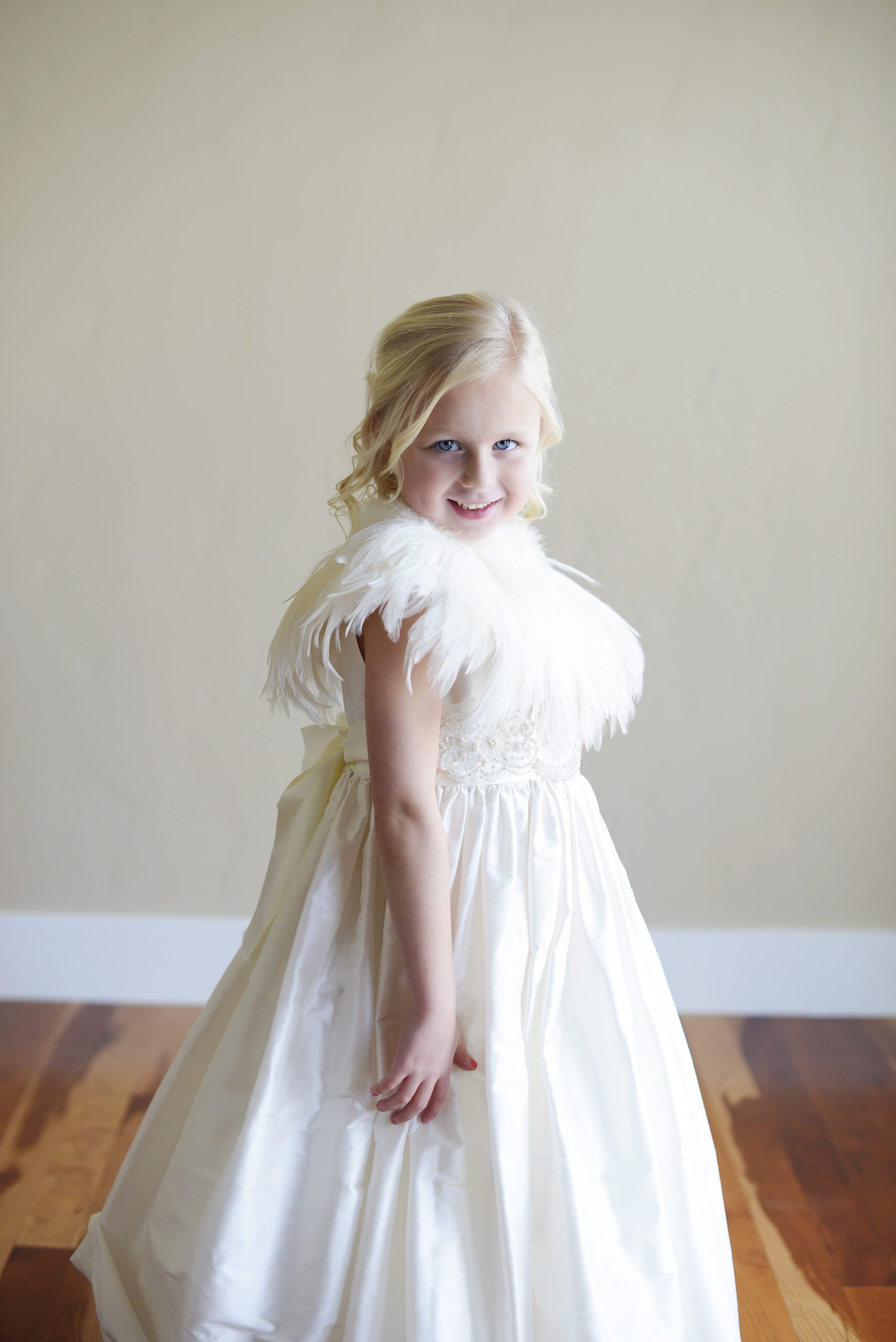 A photo of a white silk flower girl dress with a v back and ruffle collar