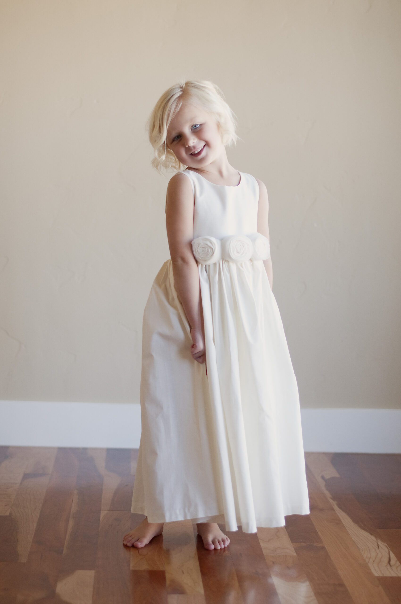 A photo fo a 5 year old flower girl wearing a pure cotton flower girl dress in a rustic style