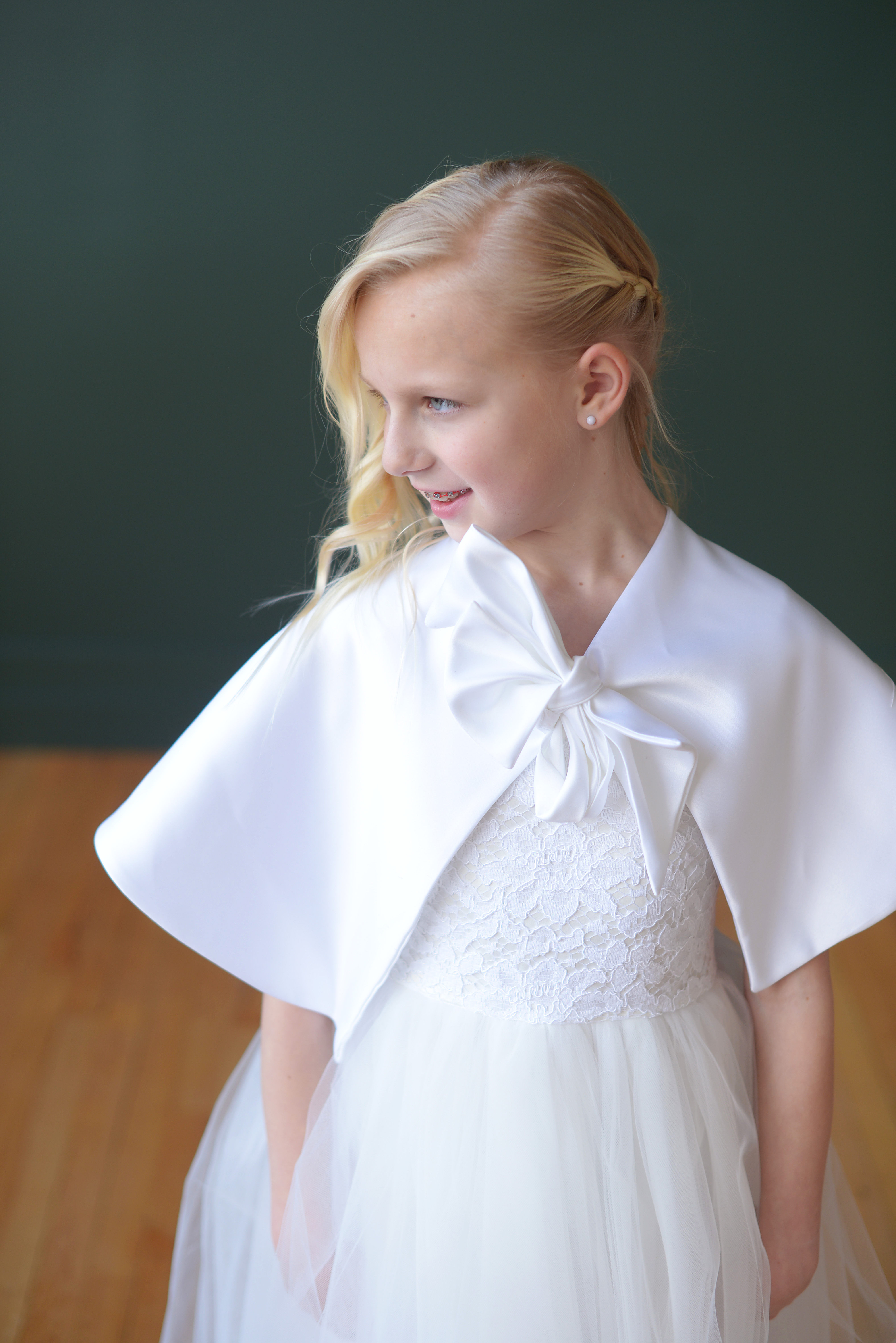 A photo of a girl wearing a first communion white satn cape