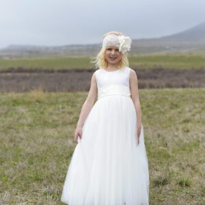 A photo of a little 5 year old girl wearing an ivory, sequin flower girl dress with a tulle skirt for twirling and a big organza flower headband